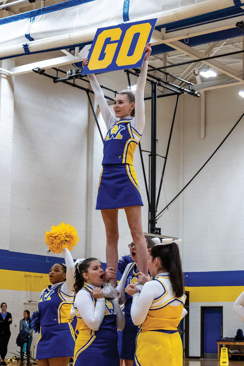 The cheer team performs an extension stunt during a pep rally. The flyer is Samantha Bailes, bases are Chloe Coleman and MacKenzie Harris, and the backspot is McKinzy Hocutt. Photo: Ron Wade.